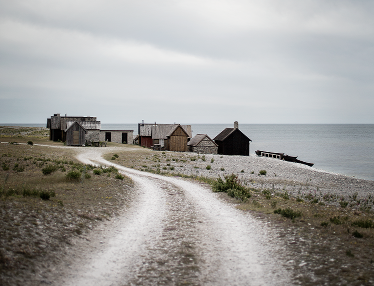 En slingrande grusväg som leder fram mot gamla fiskebodar vid havet